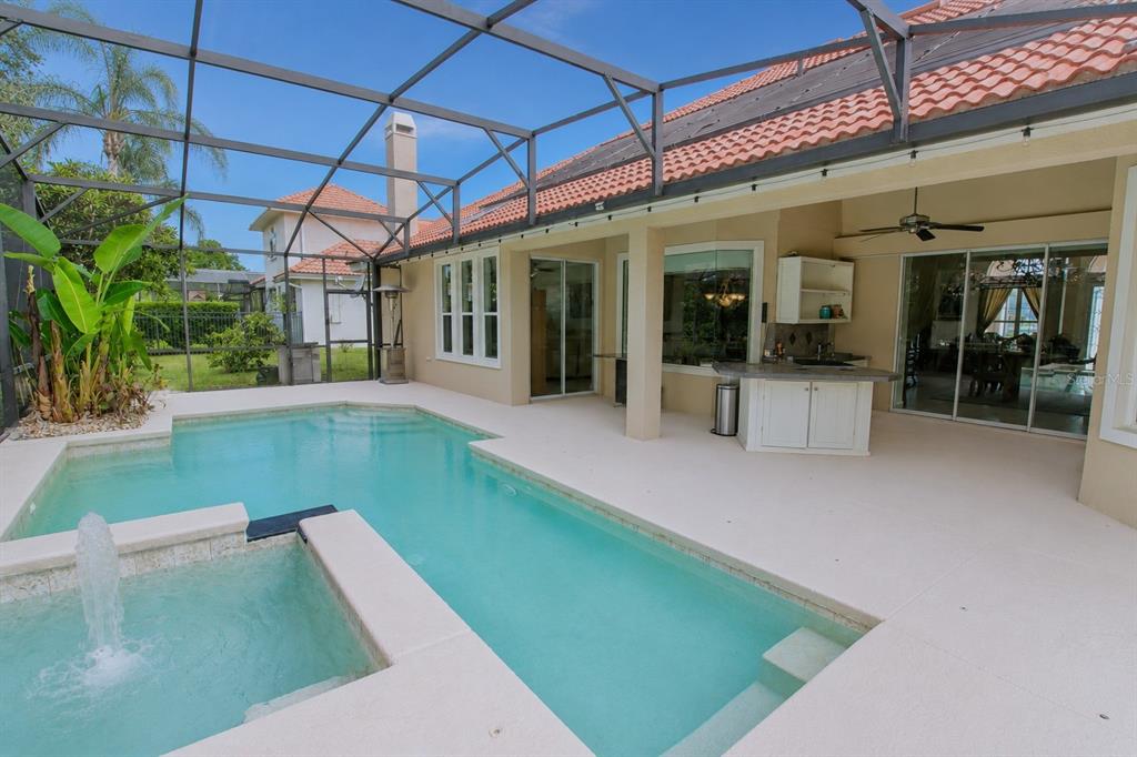 A screened-in pool area features a spa with a fountain and an outdoor kitchen — 1954 ELKHORN COURT, LONGWOOD, FL