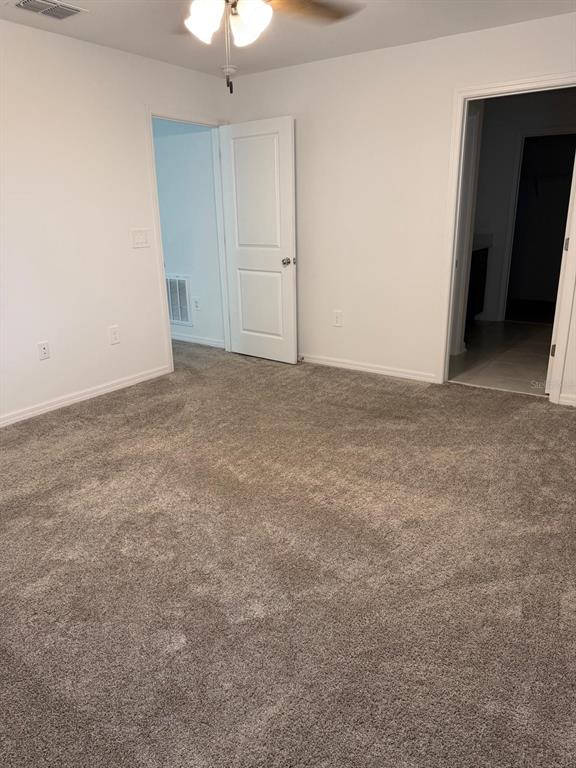 A carpeted bedroom features white walls, a ceiling fan, and two open doorways — 693 REGGIE ROAD, WINTER HAVEN, FL