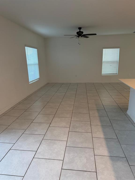 An empty room with light gray tile flooring, two windows with blinds, and a ceiling fan — 693 REGGIE ROAD, WINTER HAVEN, FL