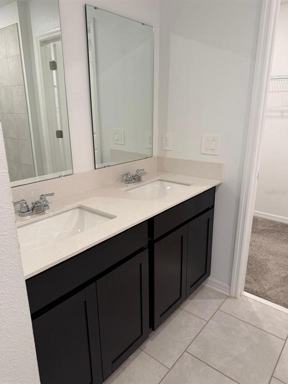 A bathroom features a double vanity with dark cabinets, a light countertop, and two mirrors — 693 REGGIE ROAD, WINTER HAVEN, FL