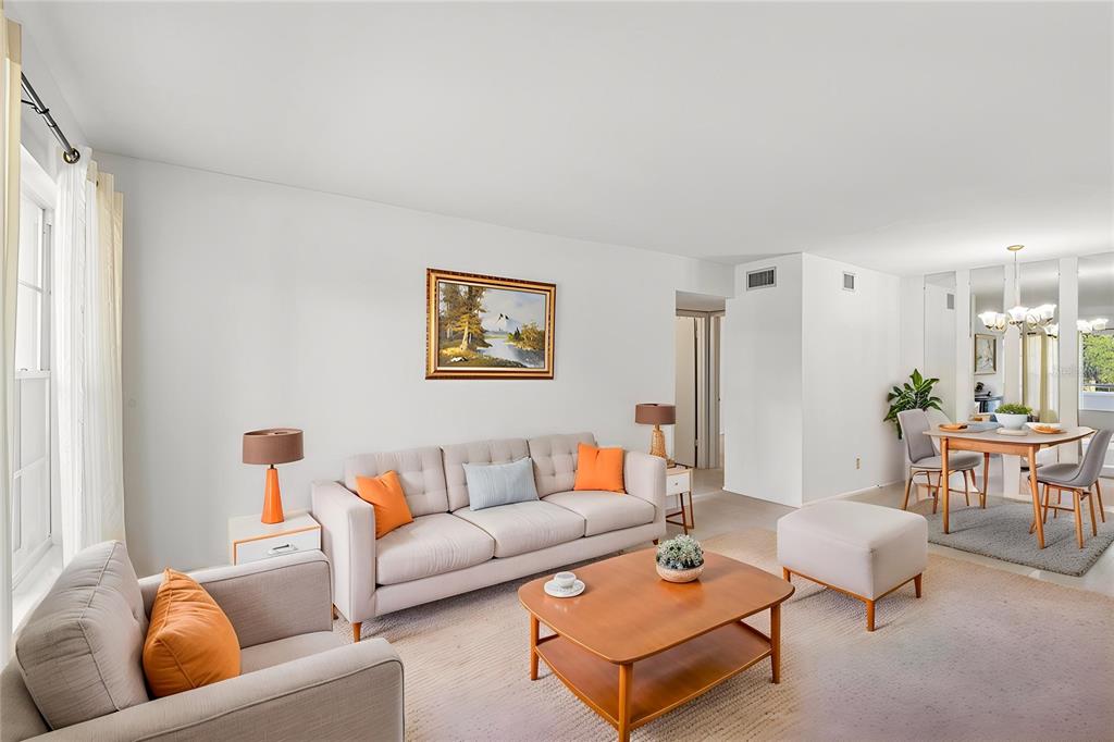 A living room with a beige sofa, matching armchair, wooden coffee table, and dining area — 2460 PERSIAN DRIVE UNIT 44, CLEARWATER, FL