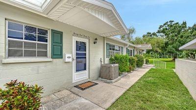 The exterior of a light-colored brick house features a front door, window, and air conditioner — 2436 GOLF COURSE DRIVE UNIT 707, SARASOTA, FL