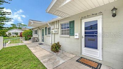 A concrete block exterior features a white front door, a small bush, and a paved walkway — 2436 GOLF COURSE DRIVE UNIT 707, SARASOTA, FL
