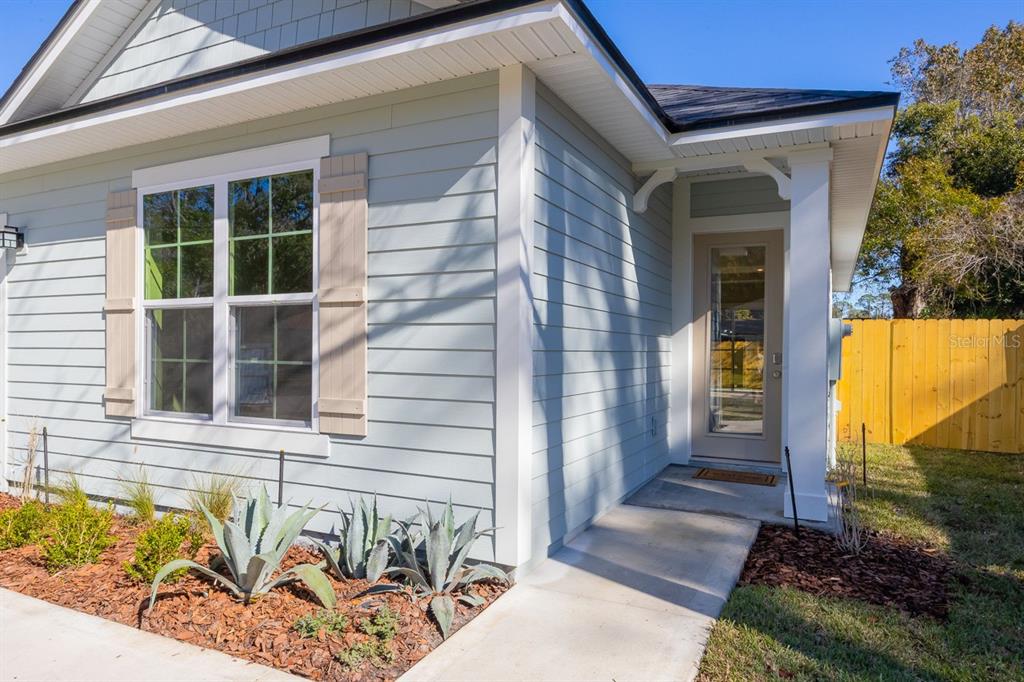 A light blue house exterior features a front door, a window with shutters, and landscaping — 102 ORANGE TREE ROAD, EAST PALATKA, FL