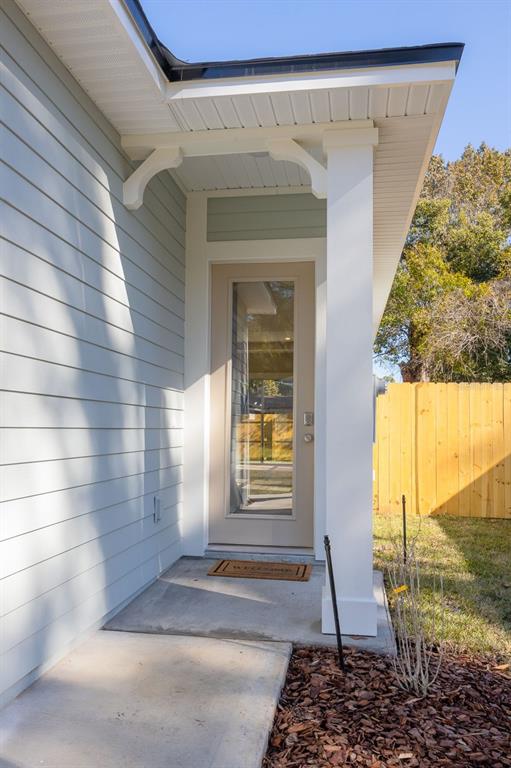 A light-colored exterior wall with a glass-paneled door sits under a covered porch entryway — 102 ORANGE TREE ROAD, EAST PALATKA, FL