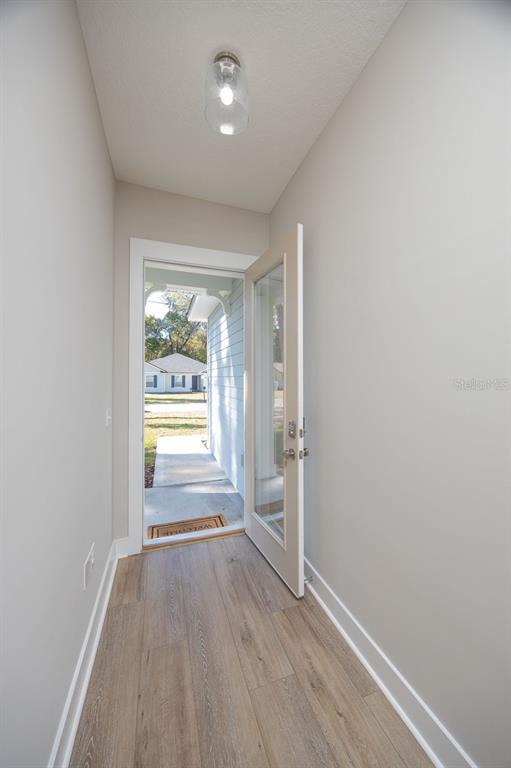 An entryway with light wood-look flooring leads to an open door showing a residential street — 102 ORANGE TREE ROAD, EAST PALATKA, FL
