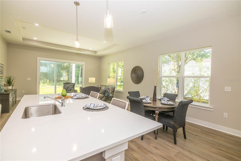 A kitchen island with a sink overlooks a dining area and a living room with windows — 102 ORANGE TREE ROAD, EAST PALATKA, FL
