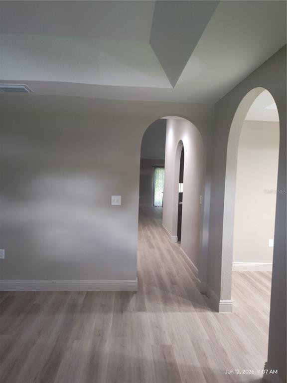 A hallway with arched doorways and light wood-look flooring connects several rooms — 13744 SE 40TH TERRACE, SUMMERFIELD, FL