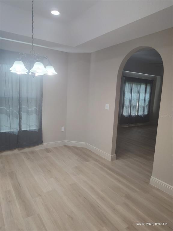 A dining room with light wood-look flooring, a tray ceiling, and an arched entryway — 13744 SE 40TH TERRACE, SUMMERFIELD, FL