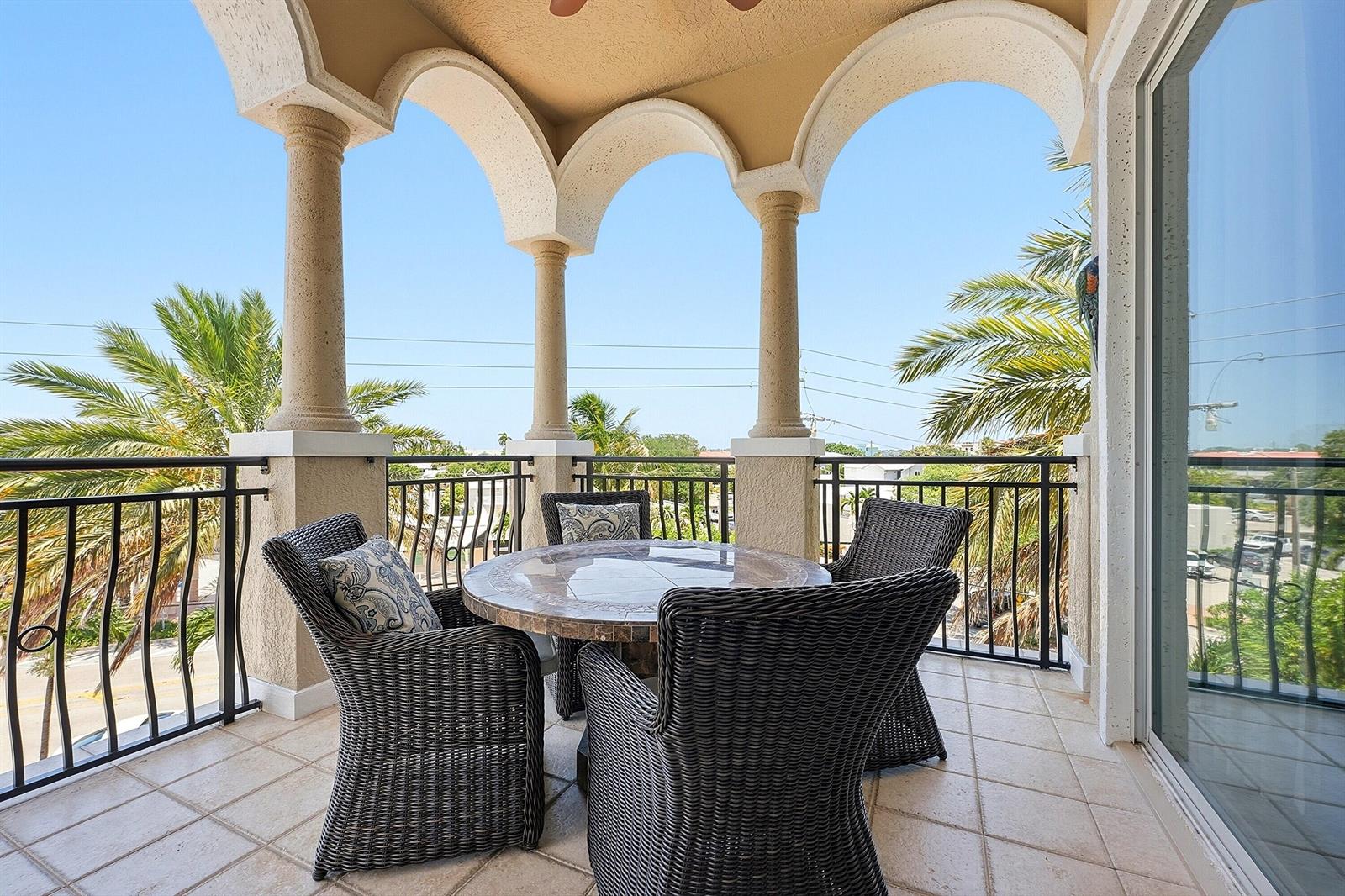 A covered balcony features a stone-topped dining set, arched columns, and a metal railing — 50 SE Ocean Boulevard # 302, Stuart FL 34994, STUART, FL