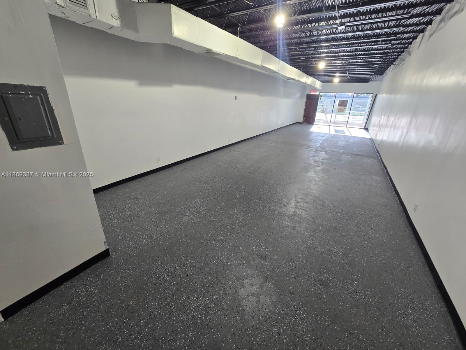An empty commercial space features white walls, a speckled gray floor, and an exposed ceiling — 2501 N State Road 7, Margate FL 33063, MARGATE, FL