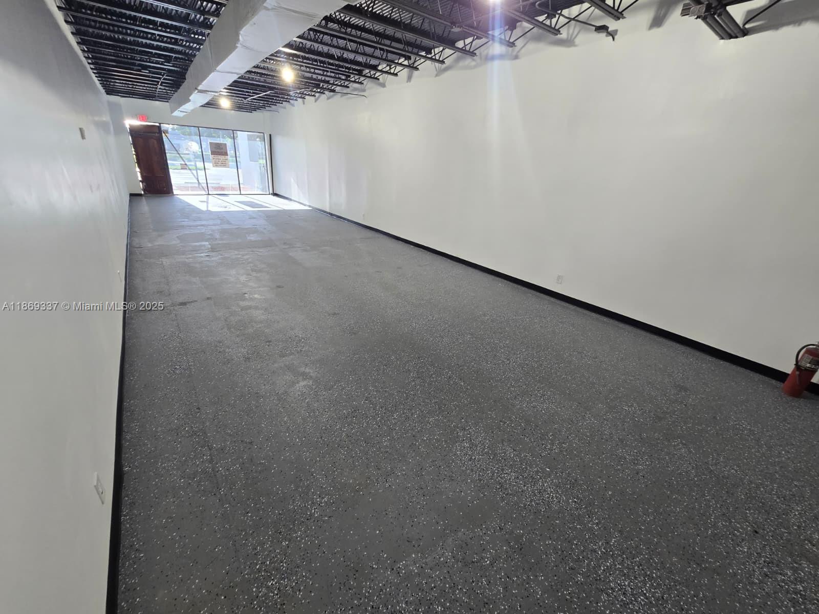 An empty commercial space features white walls, a speckled gray floor, and an exposed ceiling — 2501 N State Road 7, Margate FL 33063, MARGATE, FL