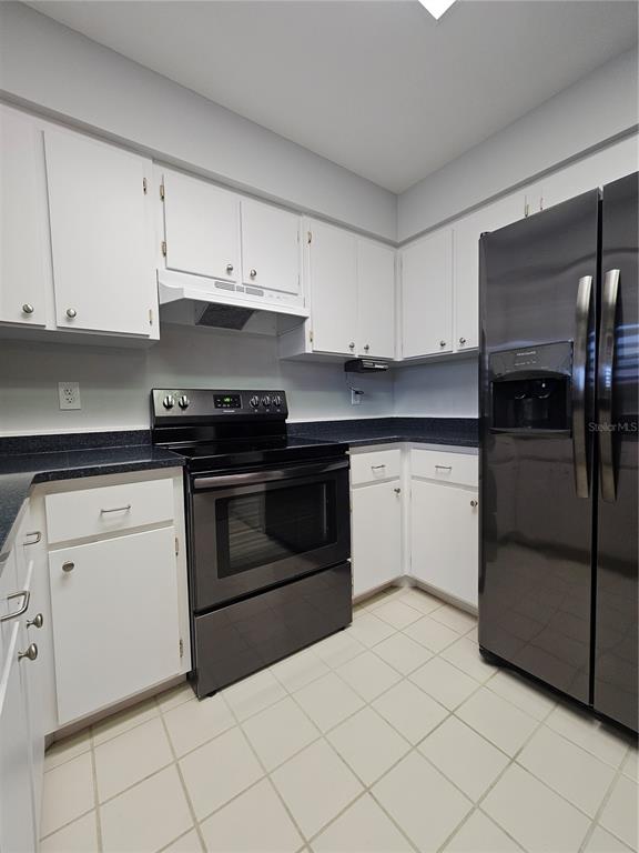 A kitchen features white cabinets, dark countertops, a black stove, and a black refrigerator — 2792 NAUTILUS DRIVE, AVON PARK, FL