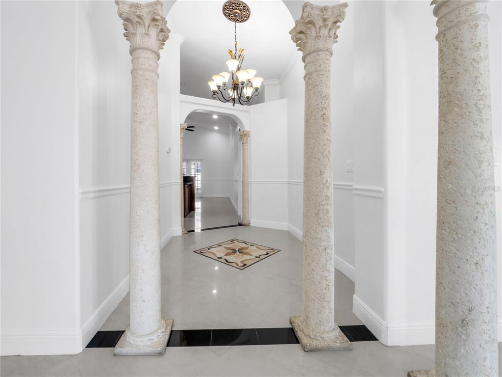 A foyer features stone columns, a chandelier, and a decorative tile inlay on the floor — 3122 W CREST AVENUE, TAMPA, FL