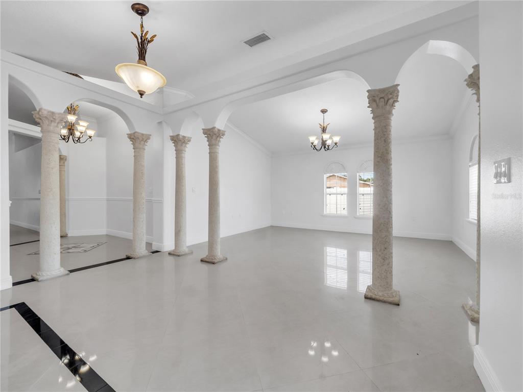 A bright, open-concept room features white walls, light tile flooring, and several decorative stone columns — 3122 W CREST AVENUE, TAMPA, FL