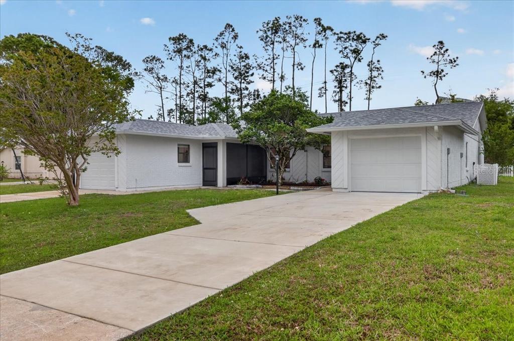 A white single-story house with two garages and a concrete driveway under a blue sky — 10 BREN MAR LANE, PALM COAST, FL