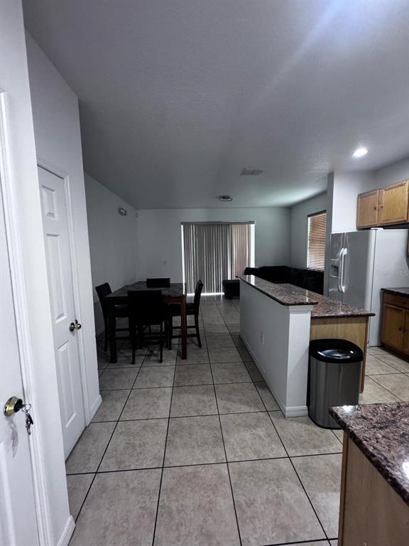 An open-concept kitchen and dining area features tile flooring, granite countertops, and sliding glass doors — 7601 ACKLINS ROAD, KISSIMMEE, FL