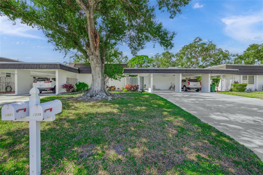 A single-story residential building with two carports, a large tree, and mailboxes in the foreground — 1325 GLEN OAKS DRIVE E UNIT 133, SARASOTA, FL
