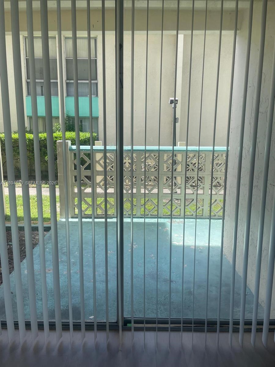 A view through vertical blinds of a small balcony with a decorative concrete railing — 2029 NW 46th Ave # E107, Lauderhill FL 33313, LAUDERHILL, FL