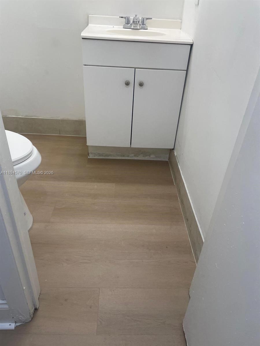 A small bathroom features a white vanity, a sink, and light-colored wood-look flooring — 2029 NW 46th Ave # E107, Lauderhill FL 33313, LAUDERHILL, FL