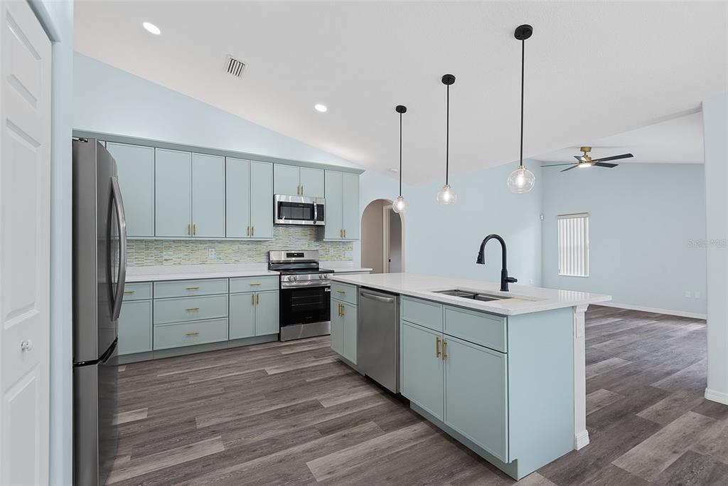 A kitchen with light blue cabinets, stainless steel appliances, and a central island with seating — 14 COLECHESTER LANE, PALM COAST, FL