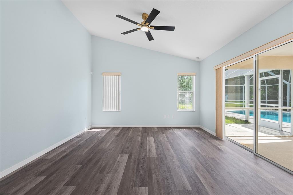 An empty room with light blue walls, wood-look flooring, a ceiling fan, and sliding glass doors — 14 COLECHESTER LANE, PALM COAST, FL