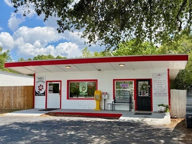 A single-story commercial building with a white facade, red trim, and a covered entrance — 1180 S MAIN STREET, BELL, FL