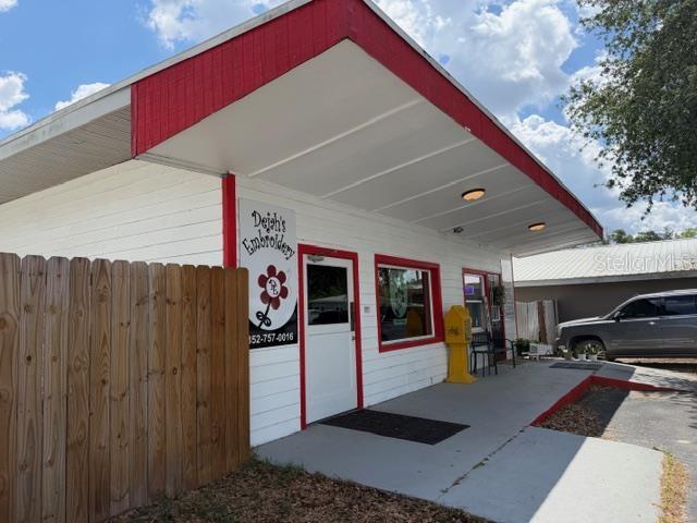 A white building with red trim and a wooden fence sits under a blue sky — 1180 S MAIN STREET, BELL, FL