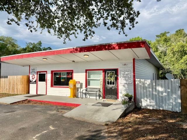 A single-story commercial building with a white facade, red trim, and a covered entrance — 1180 S MAIN STREET, BELL, FL