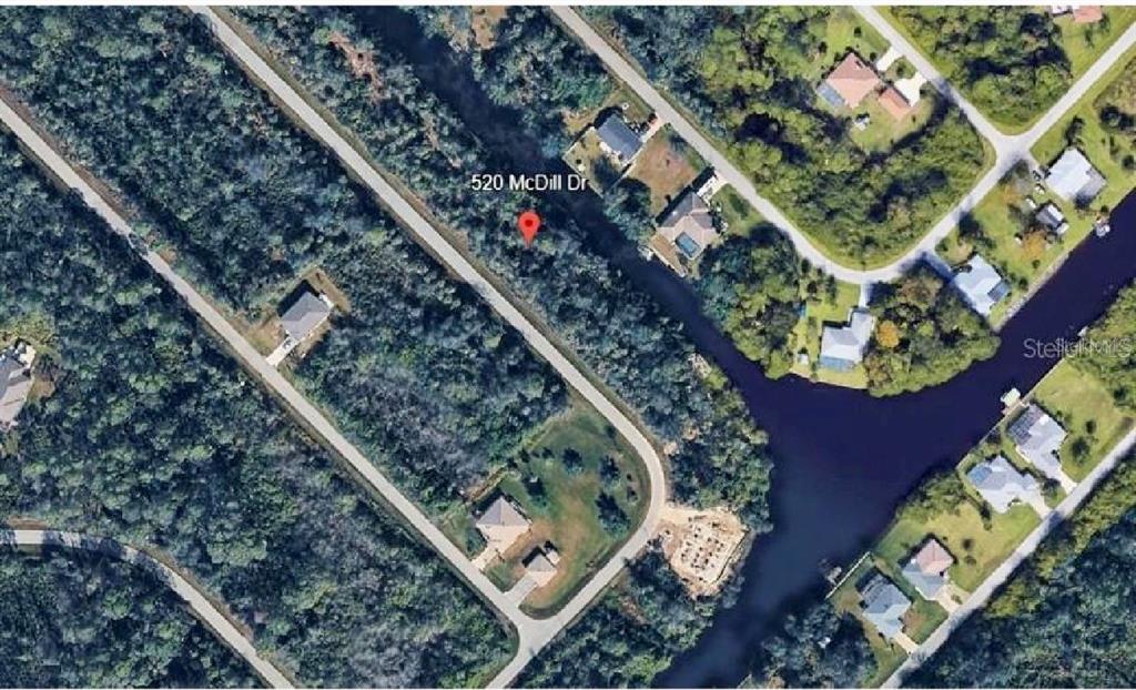 This aerial view shows a wooded residential lot located along a canal — 520 MCDILL DRIVE, PORT CHARLOTTE, FL