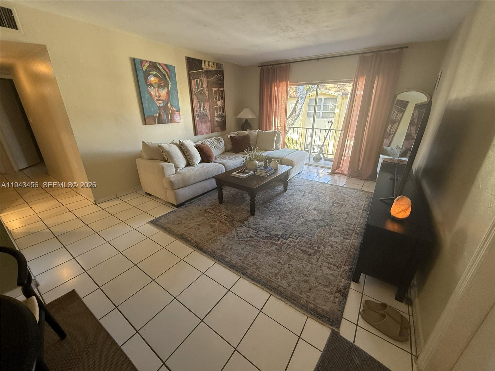 A living room features a sectional sofa, area rug, coffee table, and sliding glass doors — 7823 Miller Dr # C207, Miami FL 33155, MIAMI, FL