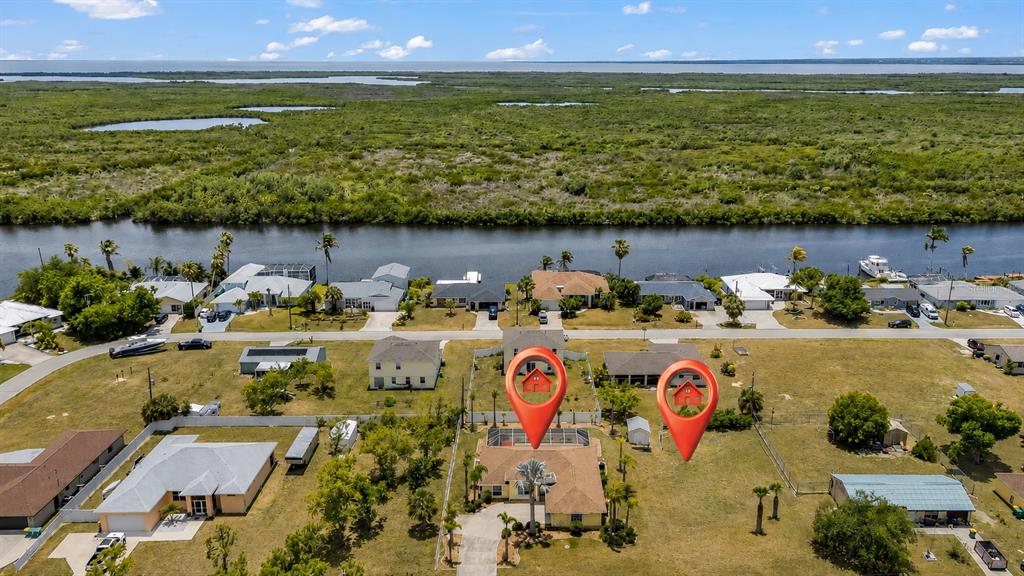 An aerial view shows a residential neighborhood with two houses highlighted by red location markers — 18075 PETOSKEY CIRCLE, PORT CHARLOTTE, FL