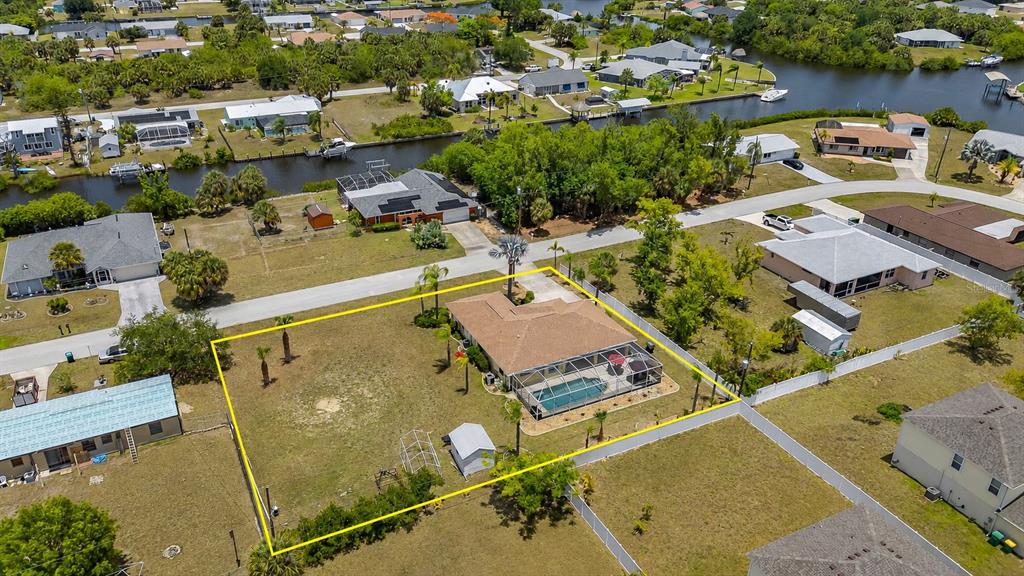 An aerial view shows a single-story house with a pool and large yard — 18075 PETOSKEY CIRCLE, PORT CHARLOTTE, FL