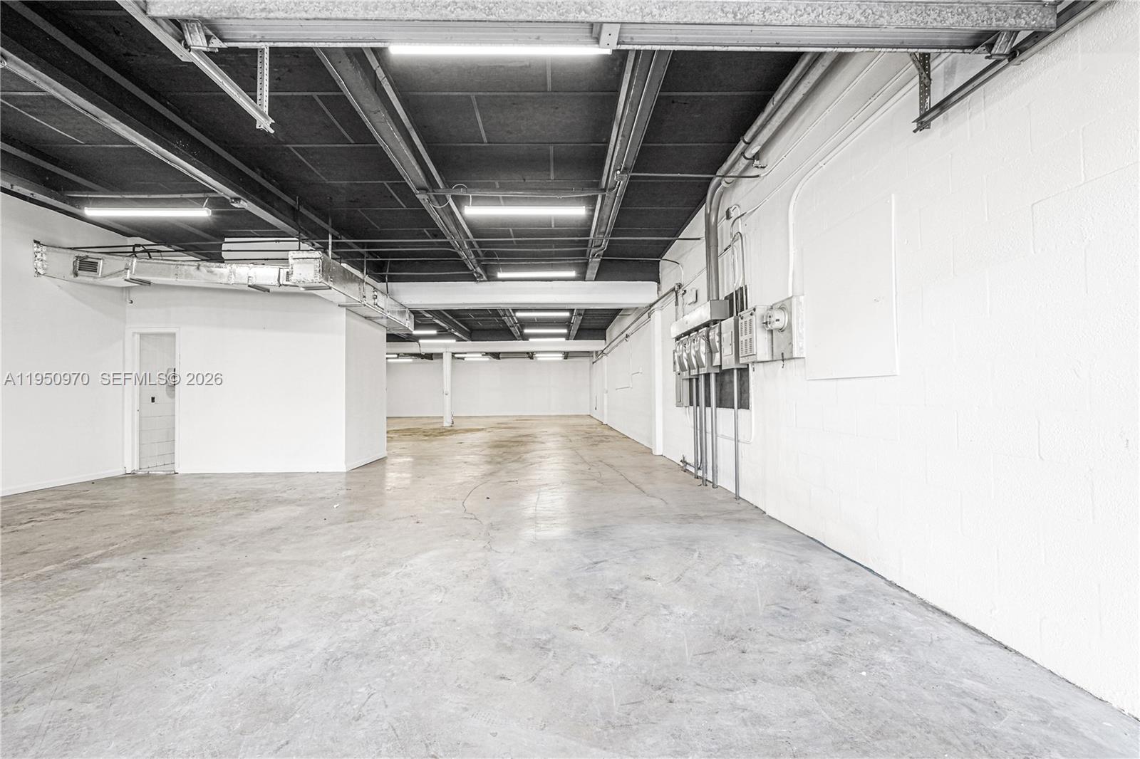 An empty industrial warehouse space features a concrete floor, white block walls, and exposed ceiling — 1822 NW 22nd St, Miami FL 33142, MIAMI, FL
