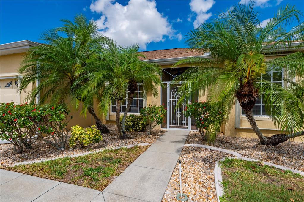A concrete walkway leads to the front entrance of a house with palm trees — 1637 PALACE COURT, PORT CHARLOTTE, FL