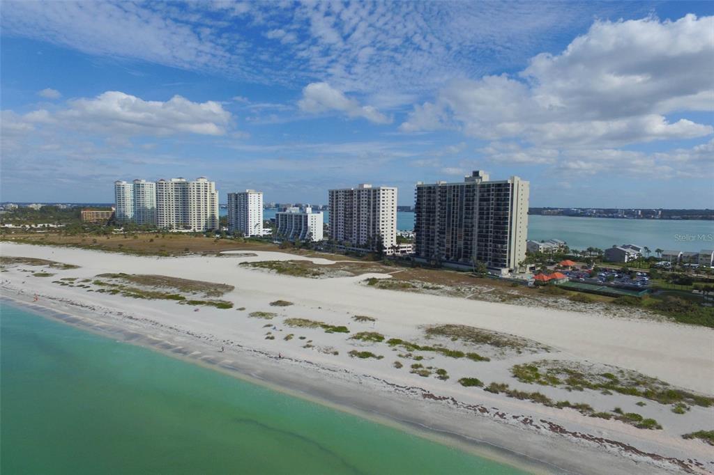 An aerial view of a sandy beach with high-rise condominiums along the coastline — 1290 GULF BOULEVARD UNIT 903, CLEARWATER BEACH, FL