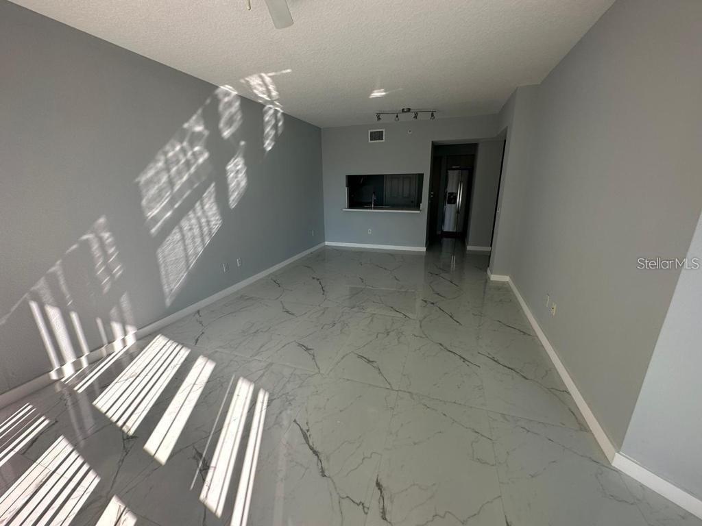 An empty living room features gray walls, a ceiling fan, and white marble-patterned tile flooring — 322 E CENTRAL BOULEVARD UNIT 905, ORLANDO, FL