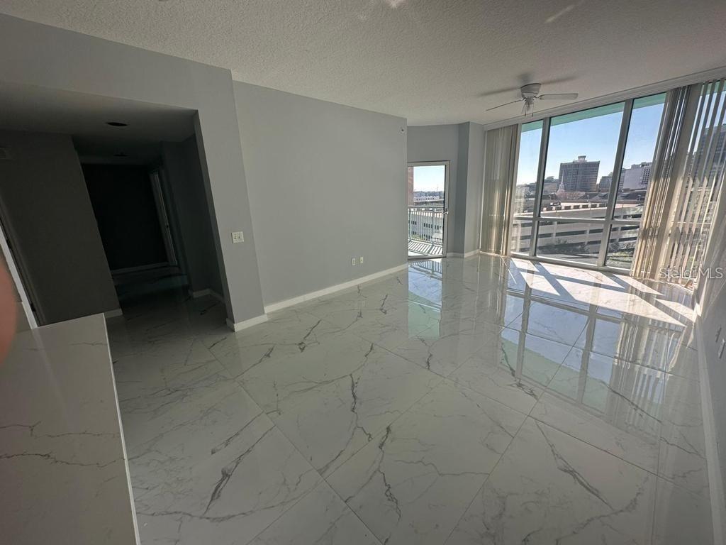 A bright living room features white marble-look tile flooring, light gray walls, and floor-to-ceiling windows — 322 E CENTRAL BOULEVARD UNIT 905, ORLANDO, FL