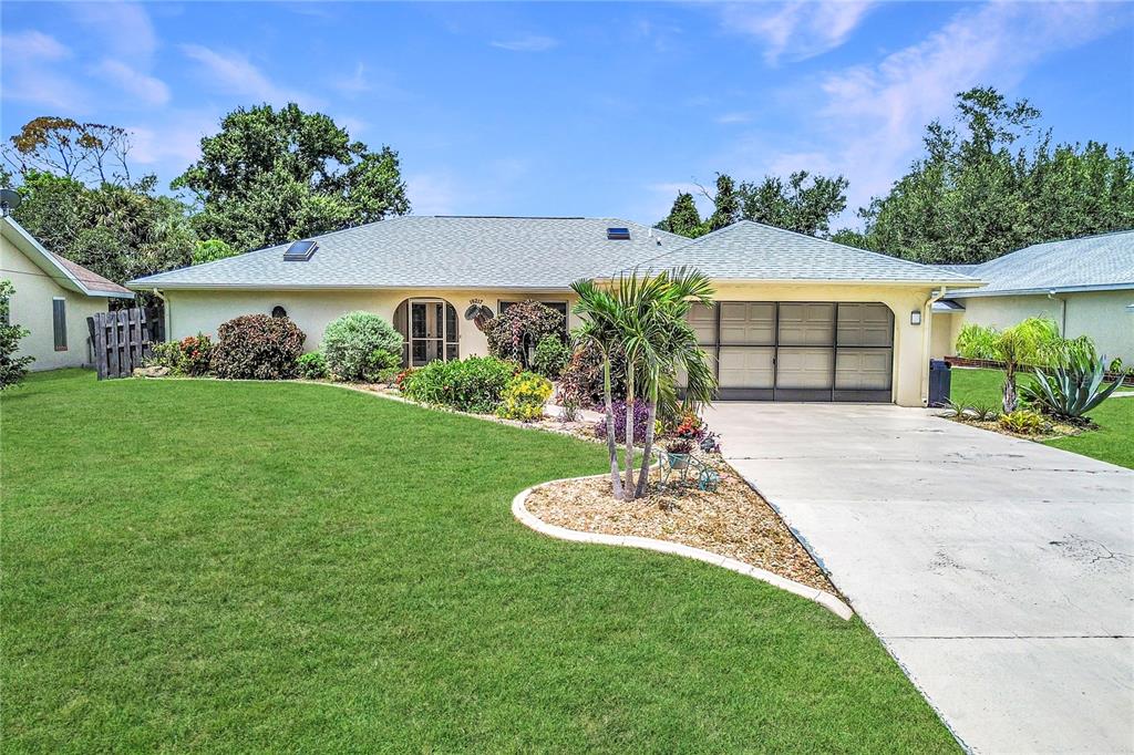 A single-story house with a light-colored exterior, a two-car garage, and a landscaped front yard — 19217 ABHENRY CIRCLE, PORT CHARLOTTE, FL