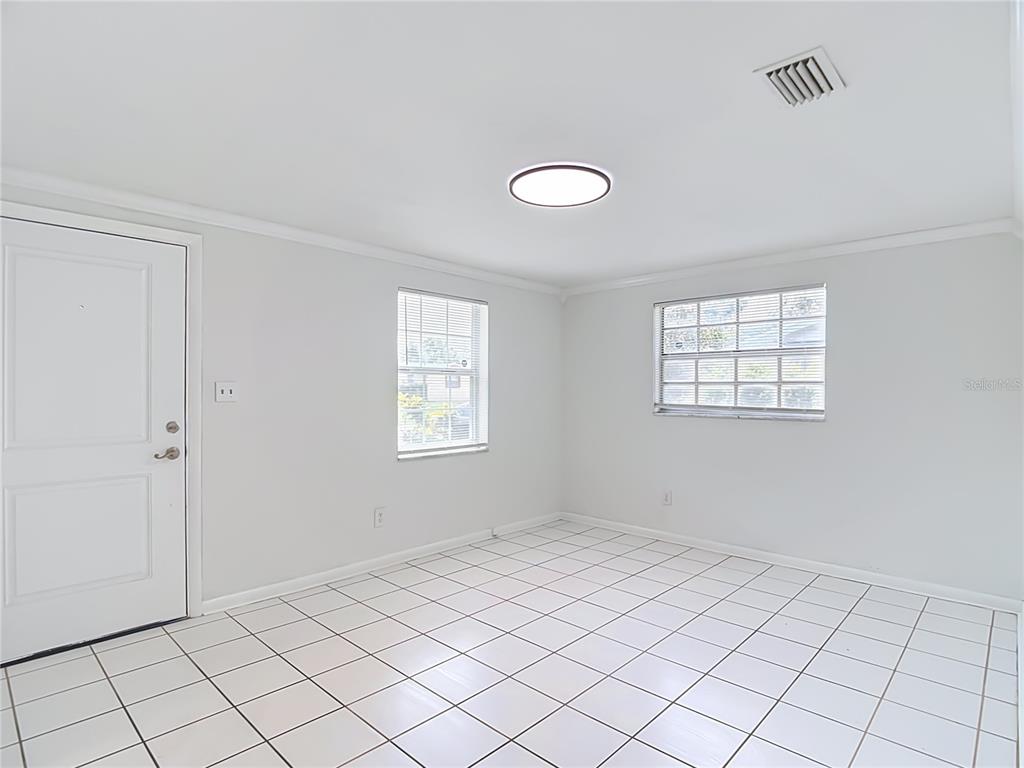 An empty room with white walls, white tile flooring, two windows, and a ceiling light — 4416 N JOHN BELL JR DRIVE, TAMPA, FL