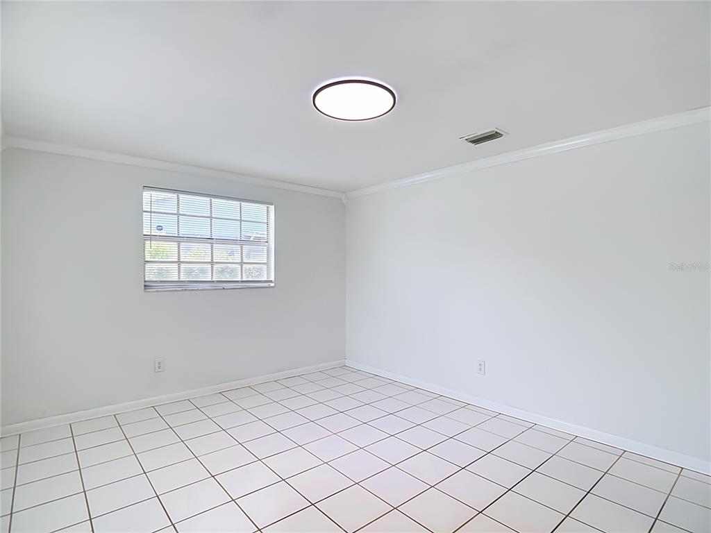 An empty room with white walls, white tiled flooring, a window, and a ceiling light — 4416 N JOHN BELL JR DRIVE, TAMPA, FL