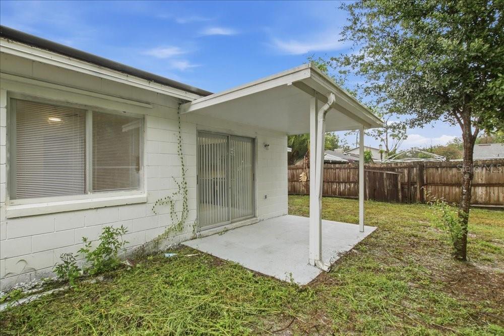 A white concrete block house features a covered patio with a sliding glass door — 8612 SPRING CONE COURT, ORLANDO, FL