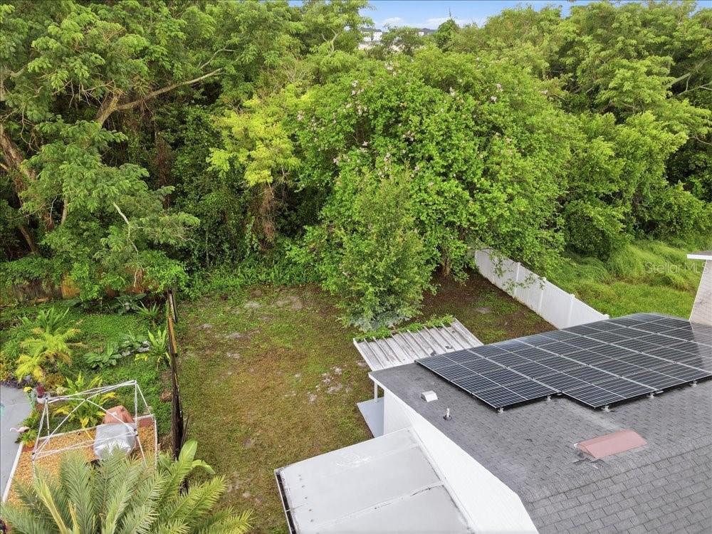 An aerial view shows a backyard with a lawn, trees, and a solar-paneled roof — 8612 SPRING CONE COURT, ORLANDO, FL