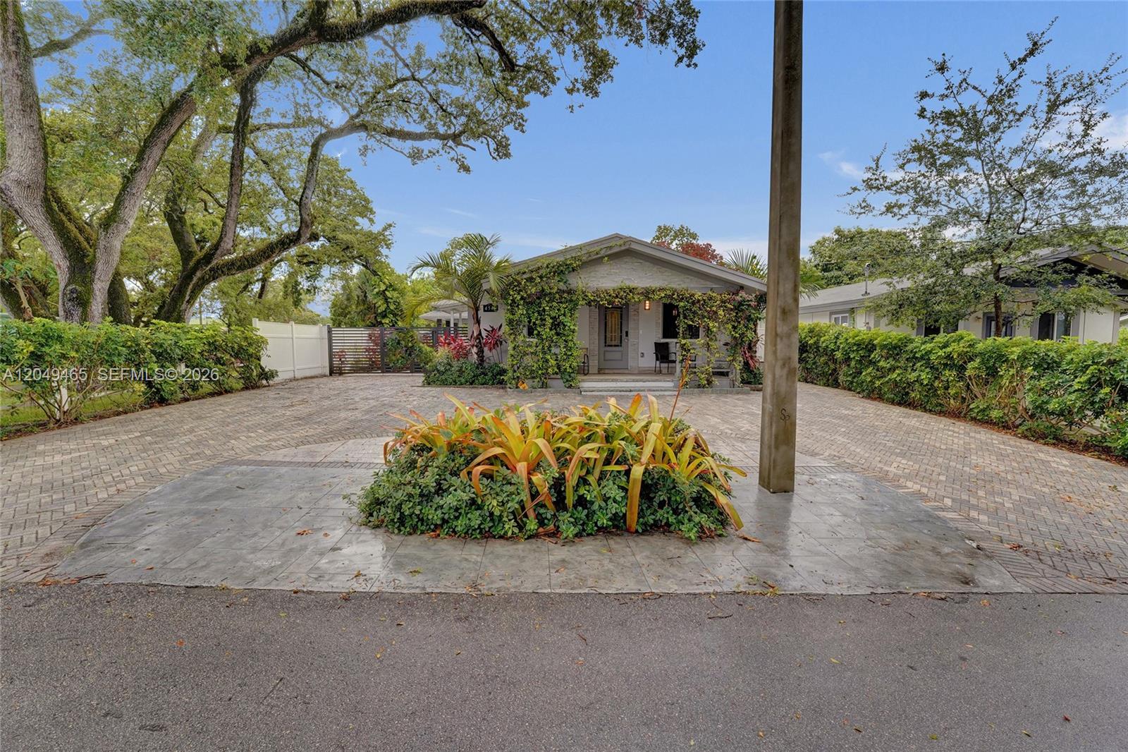 A single-story house with a paved driveway and a central garden bed in the foreground — 4541 SW 26th Ter # 0, Dania Beach FL 33312, DANIA BEACH, FL