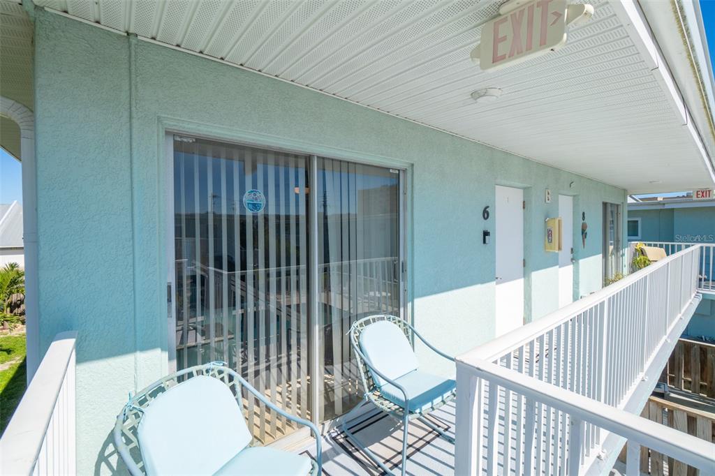 A balcony with two chairs, sliding glass doors, and unit doors numbered six and eight — 425 HARRISON AVENUE UNIT 6-2, CAPE CANAVERAL, FL