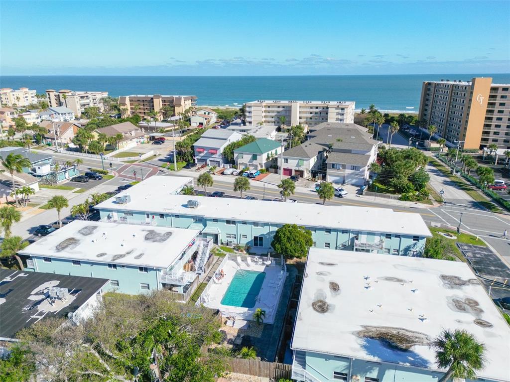 An aerial view shows a multi-unit apartment complex with a central swimming pool near the beach — 425 HARRISON AVENUE UNIT 6-2, CAPE CANAVERAL, FL