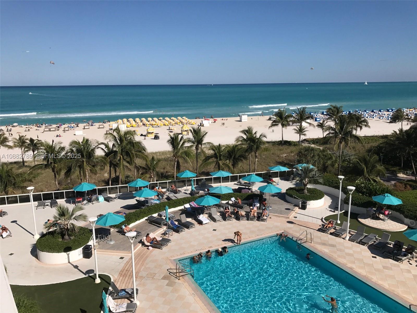 An elevated view of a swimming pool deck with lounge chairs and umbrellas overlooking the beach — 100 Lincoln Rd # 644, Miami Beach FL 33139, MIAMI BEACH, FL