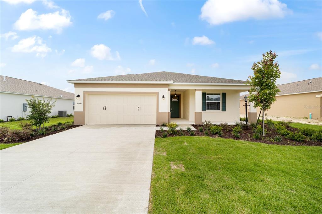 A single-story house with a beige exterior, a two-car garage, and a front lawn — 10340 SW 105TH TERRACE, OCALA, FL