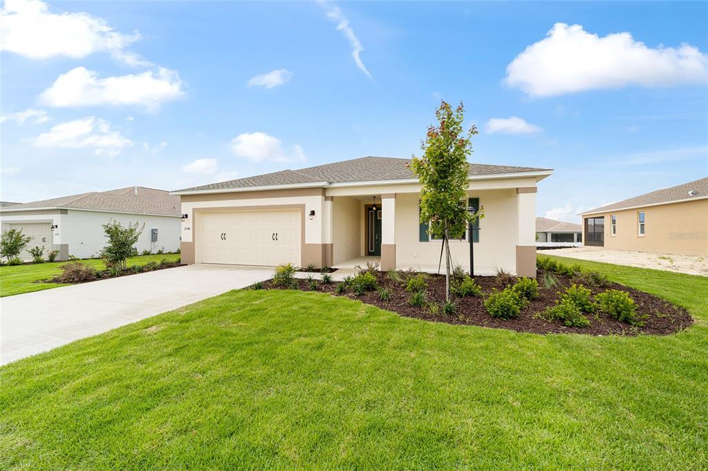 A single-story suburban house with a tan exterior, two-car garage, and a landscaped front yard — 10340 SW 105TH TERRACE, OCALA, FL
