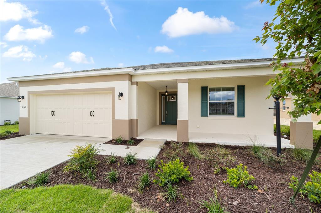 A single-story house features a two-car garage, a covered entryway, and a landscaped front yard — 10340 SW 105TH TERRACE, OCALA, FL